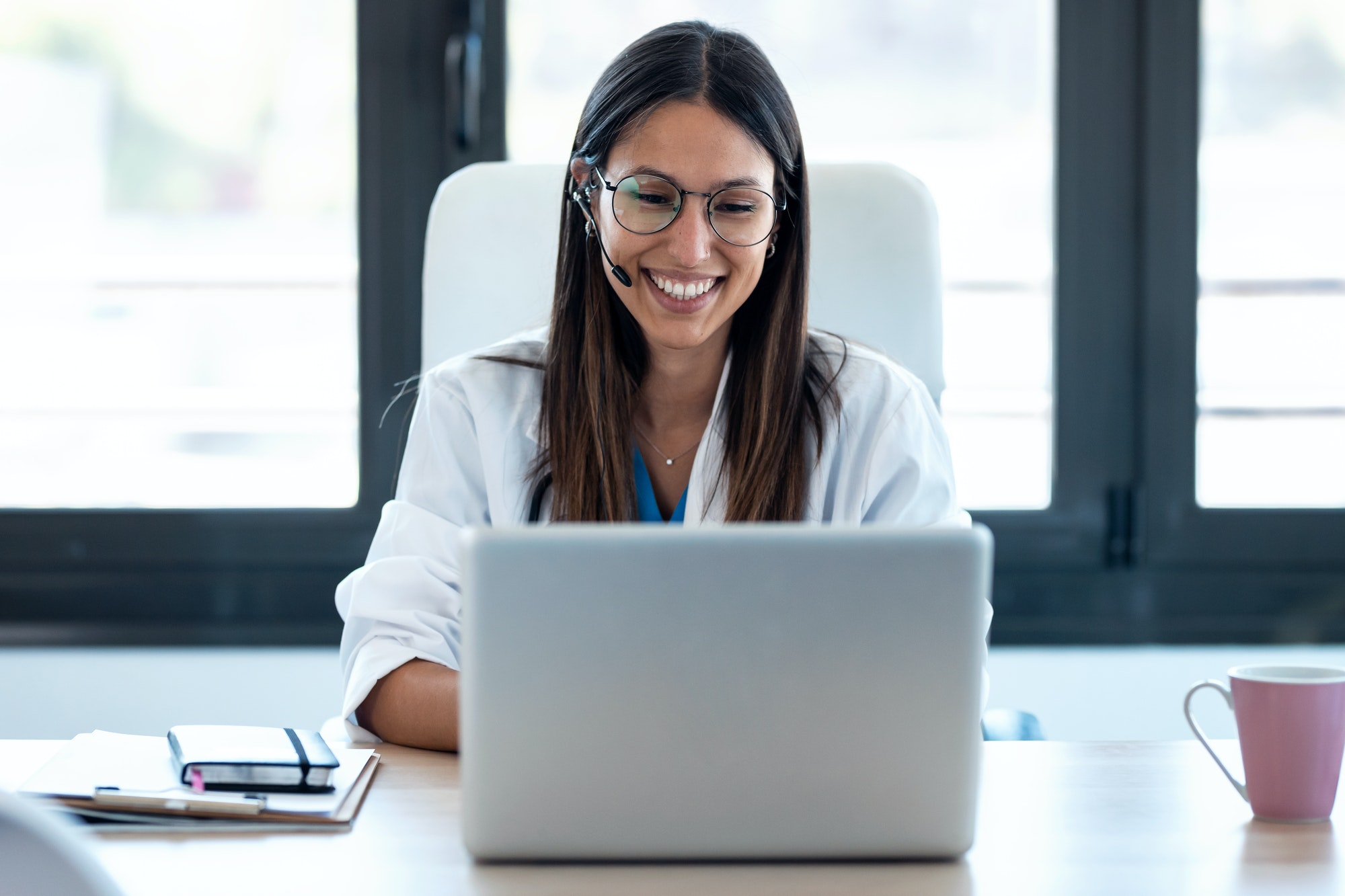 female-doctor-talking-with-colleagues-through-a-video-call-with-a-laptop-in-the-consultation-1-2.jpg